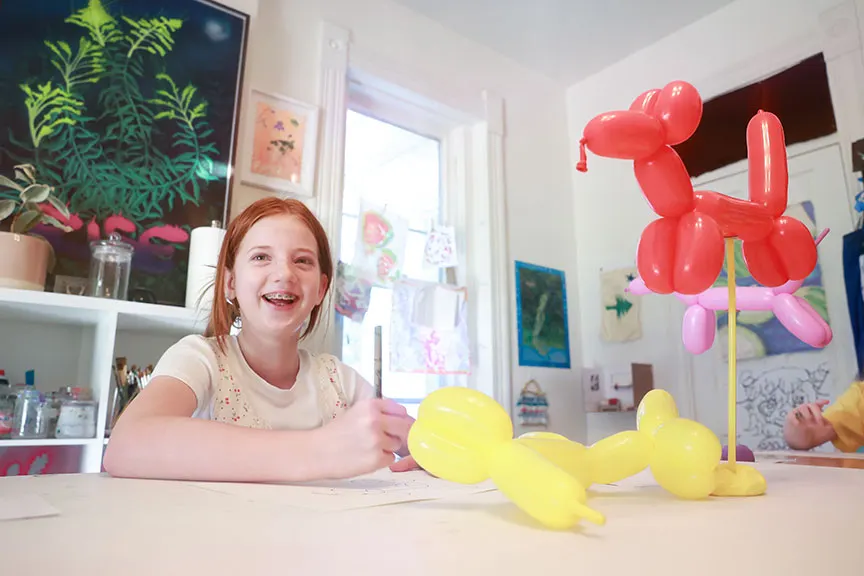 Image of a happy student drawing colorful balloon animals in the Creativity Lab studio.